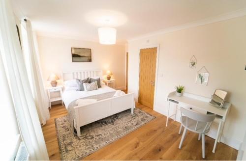a bedroom with a white bed and a desk at Foundry Farm Cottage in Hexham