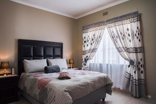 a bedroom with a large bed and a window at Rusty Estate - Self Catering in eMalahleni