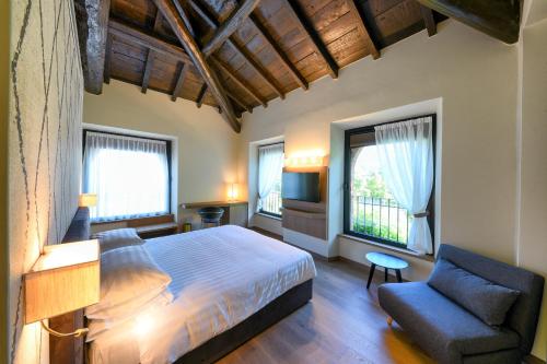 a bedroom with a bed and a chair and windows at Relais & Spa Castello di Casiglio in Erba