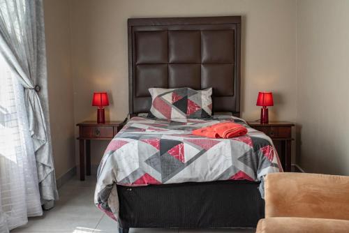 a bedroom with a bed with a quilt and two lamps at Rusty Estate - Self Catering in eMalahleni