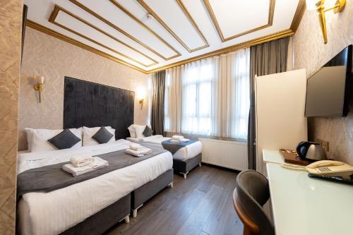 a hotel room with two beds and a desk at Diamond Royal Hotel in Istanbul