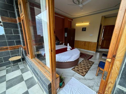 ein Zimmer mit einem Bett und einer Glastür in der Unterkunft Cafe Saffron Sips & Stays - Alpine Suites Naggar Near Manali in Nagar