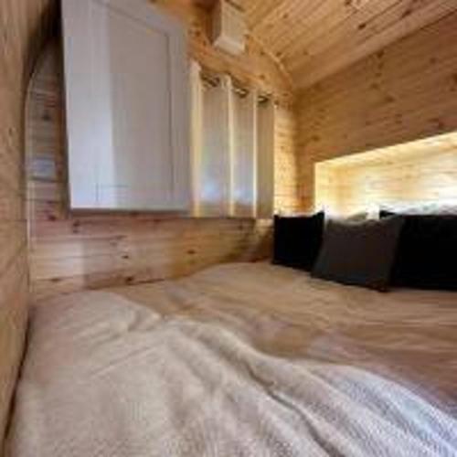 a bedroom with a large bed in a wooden room at Foundry Farm Arch- pod inspired home in Hexham