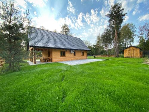 a wooden cabin in a field of green grass at Radość o poranku in Smardzew