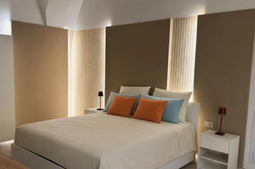 a bedroom with a white bed with orange and blue pillows at Passo Lento Charme Rooms in Gravina in Puglia