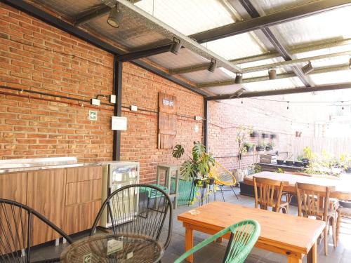 LOPEZ Hostel & Suites في بوينس آيرس: فناء به طاولات وكراسي وجدار من الطوب