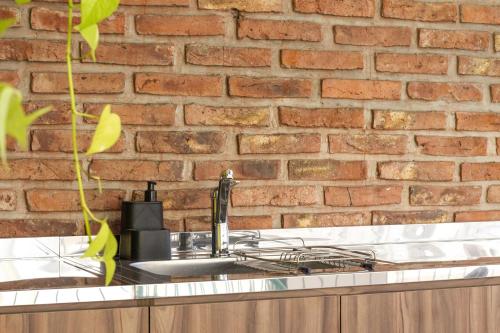 LOPEZ Hostel & Suites في بوينس آيرس: حوض مطبخ مُلاصق لجدار من الطوب