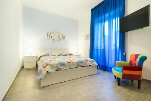 a bedroom with a bed and a chair at Talia Ortigia Apartment in Syracuse