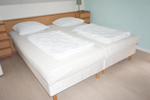 a bed with white sheets and pillows on it at Kustverhuur, Park Schoneveld, Stern 233 in Breskens