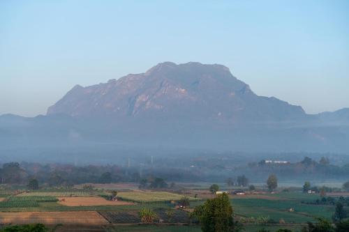a mountain in the middle of a field with a fog at PATTA Hideaway Chiang Dao in Chiang Dao