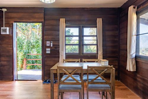 a dining room with a table and two windows at PATTA Hideaway Chiang Dao in Chiang Dao