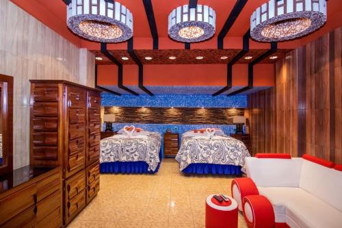 a bedroom with two beds and a couch and chairs at Hotel La Cabaña in Ciudad Melchor de Mencos