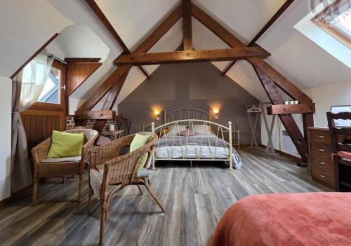 a bedroom with a bed and chairs in a attic at Ferme de la Forterie Verlinghem in Verlinghem