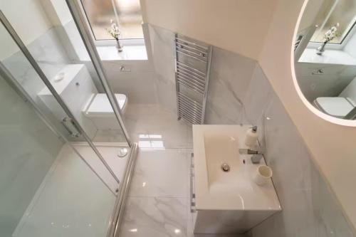a white bathroom with a sink and a mirror at Foundry Farm Apartment in Hexham