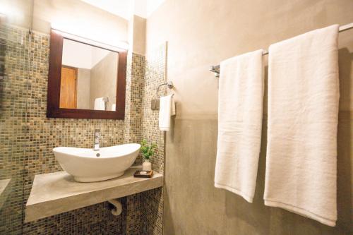 a bathroom with a sink and a mirror and towels at 100Steps Mirissa in Mirissa