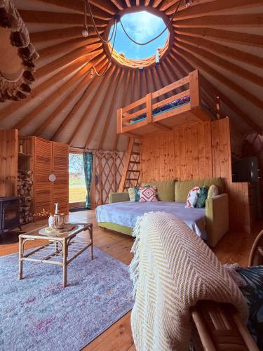 a living room with a bed and a couch and a table at Glamping Niebiańska Osada Jurty Dolnośląskie in Polanica-Zdrój