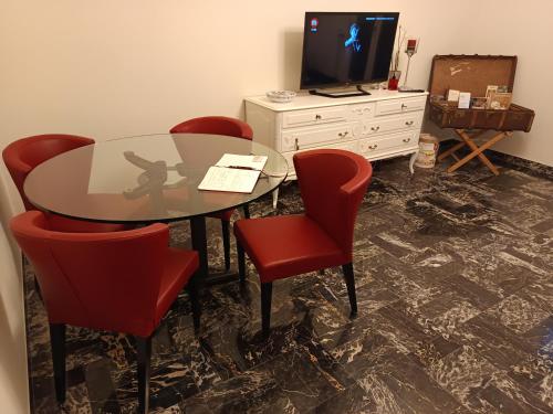 a dining room with a glass table and red chairs at A Casa di Luca in Faenza