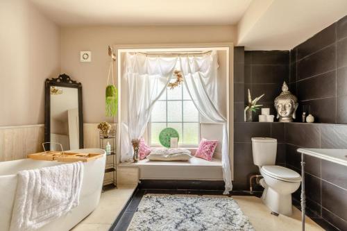 a bathroom with a window with a tub and a toilet at 4 Bed in Barnstaple oc-n34877 in Tawstock