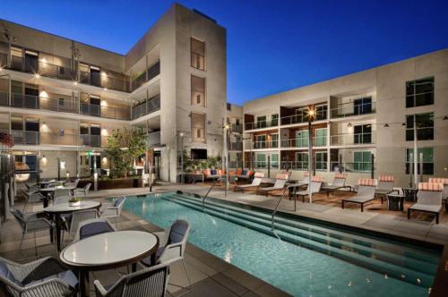 a pool with tables and chairs next to a building at Luxury Penthouse 2-BR - with Pool & Gym Access in Los Angeles