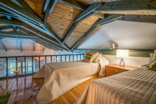 two beds in a room with a wooden ceiling at San Antonio Villas in Pandokrátor