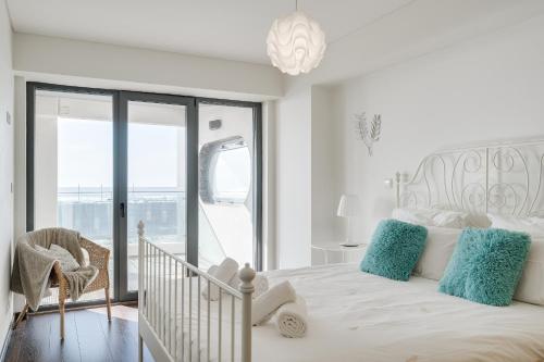 a white bedroom with a bed with blue pillows at luxury Plazza Sea view in Costa da Caparica