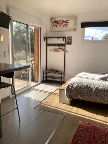 a bedroom with a bed and a desk and a window at Le studio de St Martin in Saint-Martin-de-lʼArçon
