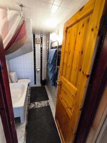 a bathroom with a wooden door and a sink at Lugnt gästhus nära hav, natur och vandring in Glumslöv