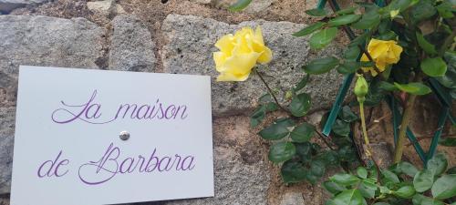 a sign and a yellow rose on a stone wall at La Maison de Barbara in La Guiche