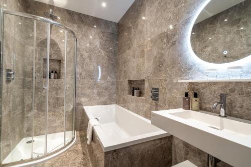 a bathroom with a tub and a sink and a shower at No1 The Mansions By Mansley in London