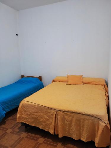 a bedroom with two beds and a white wall at Cactus del Valle 2 in Tinogasta