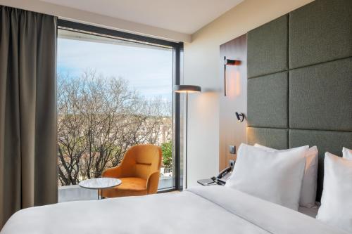 a hotel room with a bed and a chair and a window at Radisson Blu Hotel, Montpellier in Montpellier