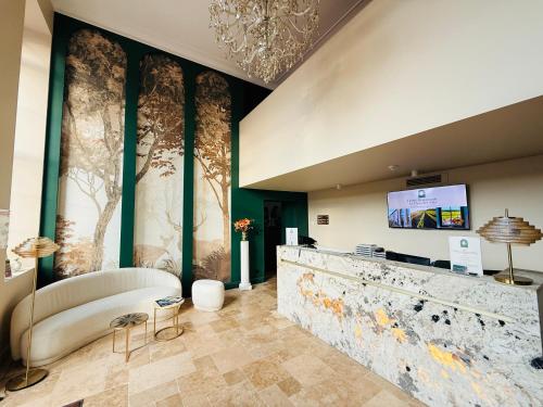 a lobby with a couch and a tv on a wall at Hôtel Le Clos des Arts in Gevrey-Chambertin