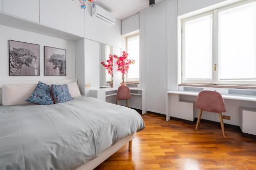 a bedroom with a bed and two chairs and windows at Imperial Terrace suite in Milan