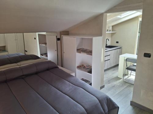 a bedroom with a large bed and a kitchen at Il Nido della Piazzetta in Saluzzo