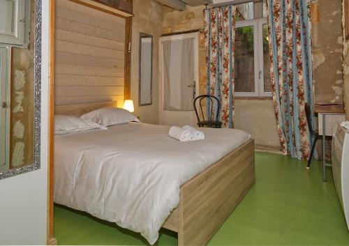 a bedroom with a bed with white sheets and a green floor at La Chancellerie in Loches