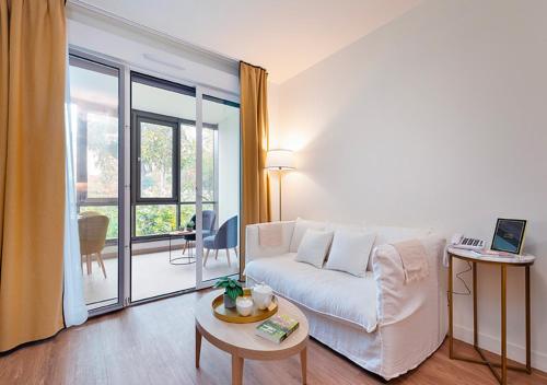 a living room with a white couch and a table at Zenao Appart'hôtels Saint-Mandé in Saint-Mandé