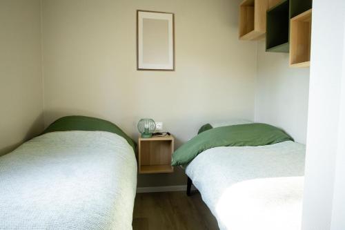 two twin beds in a room with a mirror at Chalet Bosrijk in Haarle