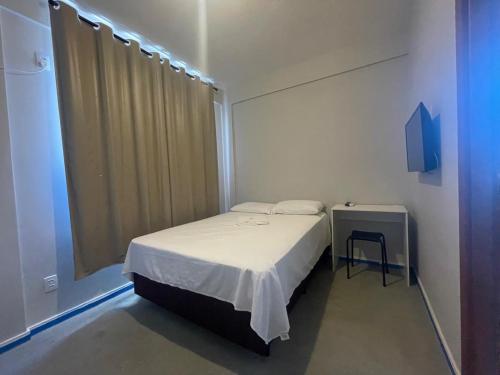 a small bedroom with a bed and a window at Pousada Catarina in Biguaçu