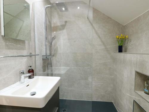 a white bathroom with a sink and a shower at Maelog, 14 Tides Reach in Rhosneigr