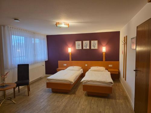 a bedroom with two beds and a table and a chair at Gasthof Waldesruh in Saerbeck
