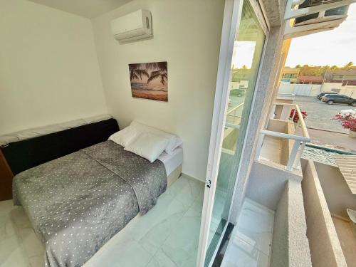 a small bedroom with a bed and a balcony at Diamante dos Ventos Duplex com Piscina Cumbuco in Caucaia