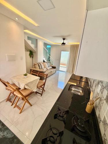 a kitchen and living room with a table and a stove at Diamante dos Ventos Duplex com Piscina Cumbuco in Caucaia
