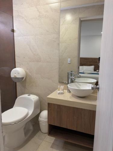 a bathroom with a toilet and a sink and a mirror at Hotel Chayrama in Santa Marta