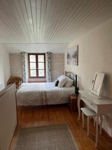 a bedroom with a bed and a desk with a computer at Maison du Figuier 1799 in Nanclars