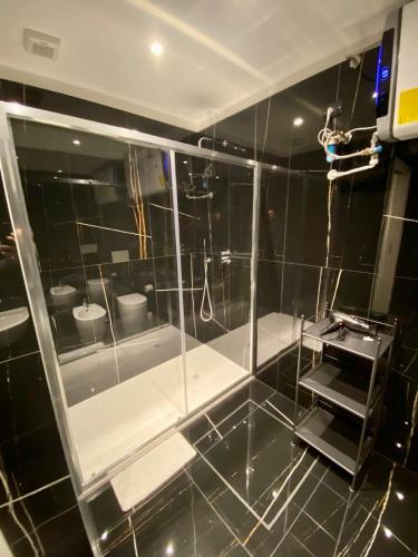 a black tiled bathroom with a glass shower stall at ANTONELLA's ROOM in Bresso