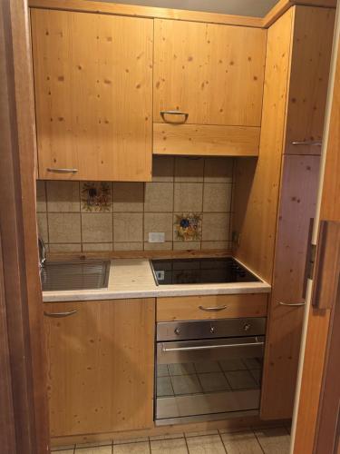 a kitchen with wooden cabinets and a stove at Campiglio Monolocale Cima Tosa in Madonna di Campiglio