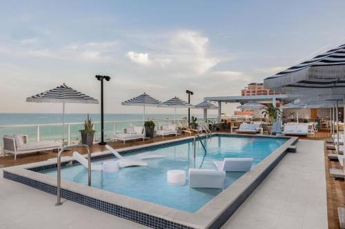 a swimming pool with chairs and umbrellas at a hotel at The Hiatus Clearwater Beach, Curio Collection By Hilton in Clearwater Beach