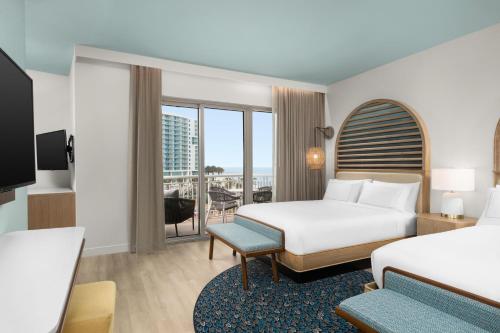 a hotel room with two beds and a balcony at The Hiatus Clearwater Beach, Curio Collection By Hilton in Clearwater Beach