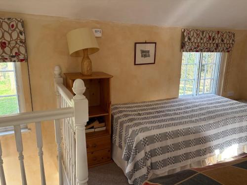 a bedroom with a bed and a lamp and windows at The Old Post Office, Hilton in Huntingdon