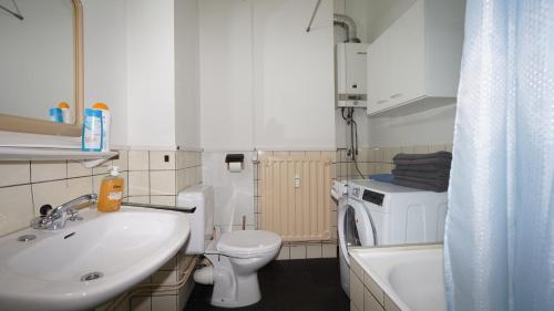 a bathroom with a sink toilet and a washing machine at Plantin Apartment in Antwerp